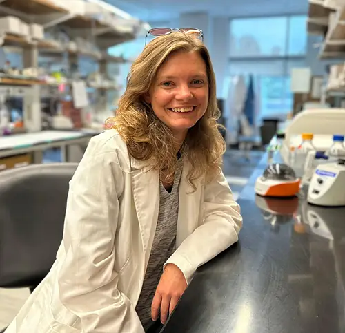 A woman in a labcoat posing for a photo in the lab