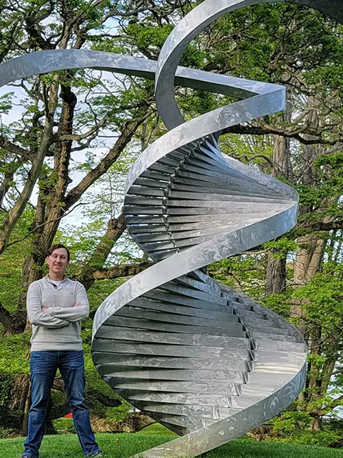 A man standing next to a statue of a DNA helix